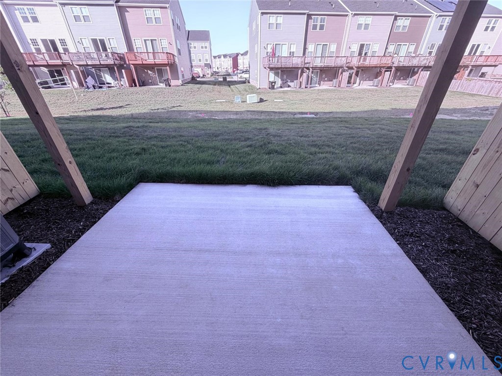 Concrete patio featuring wooden support beams and an open grass area Concrete patio featuring wooden support beams and an open grass area