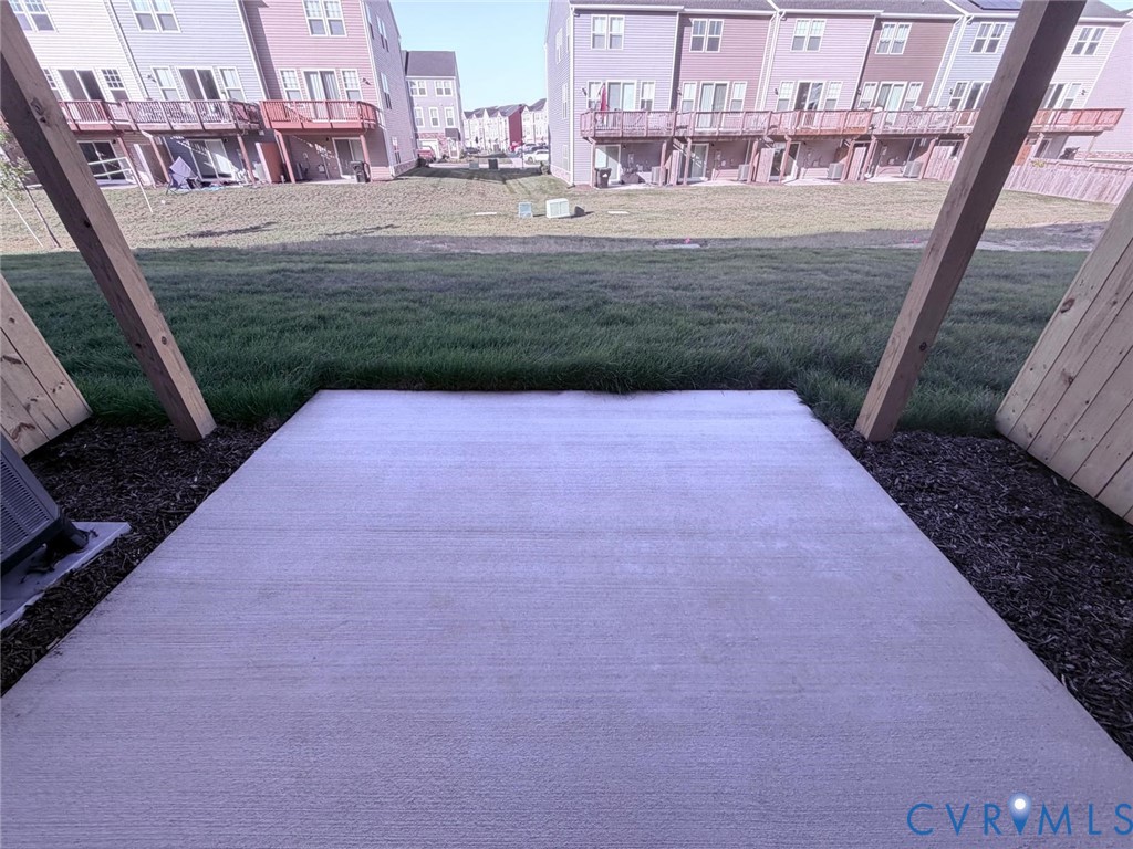 Concrete patio featuring wooden support beams and an open grass area Concrete patio featuring wooden support beams and an open grass area