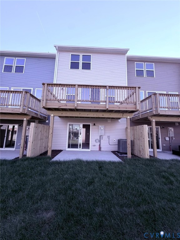 Multi-level townhome exterior featuring horizontal siding, an elevated wood deck, a concrete ground-level patio, and wood privacy fencing Multi-level townhome exterior featuring horizontal siding, an elevated wood deck, a concrete ground-level patio, and wood privacy fencing