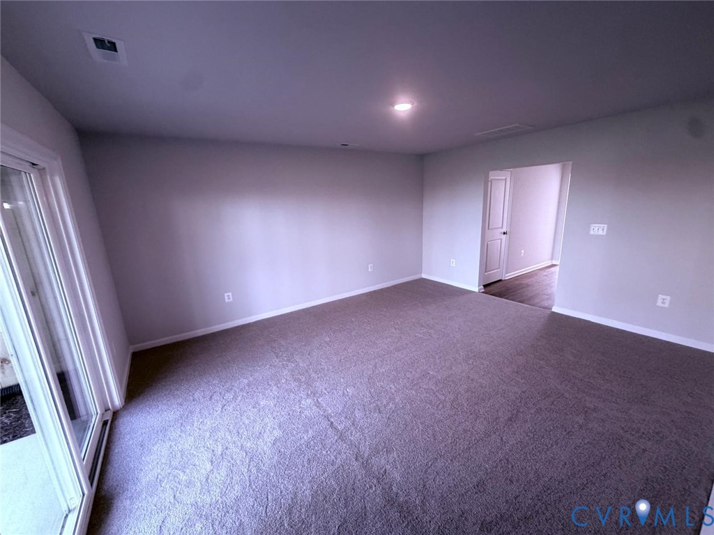 Neutral-toned interior space featuring wall-to-wall carpeting, sliding glass doors, recessed lighting, and a multi-panel interior door Neutral-toned interior space featuring wall-to-wall carpeting, sliding glass doors, recessed lighting, and a multi-panel interior door