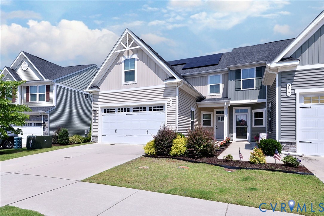 Two-story residence featuring horizontal siding, gable rooflines, solar panels, and an attached multi-car garage with carriage-style hardware