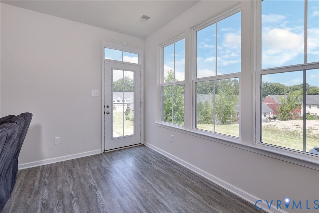 Sunroom featuring wood-finish flooring, extensive multi-pane windows, and a glass-paneled exterior door