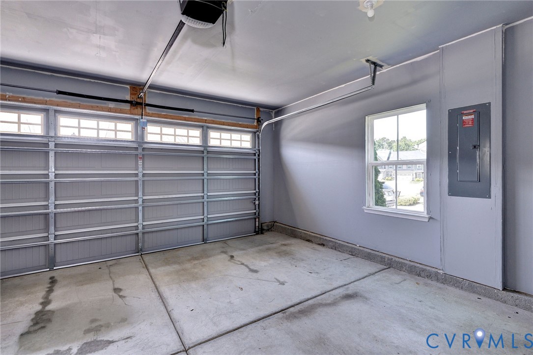 Garage featuring a sectional overhead door with paneled windows, interior window with grid muntins, and a wall-mounted electrical panel