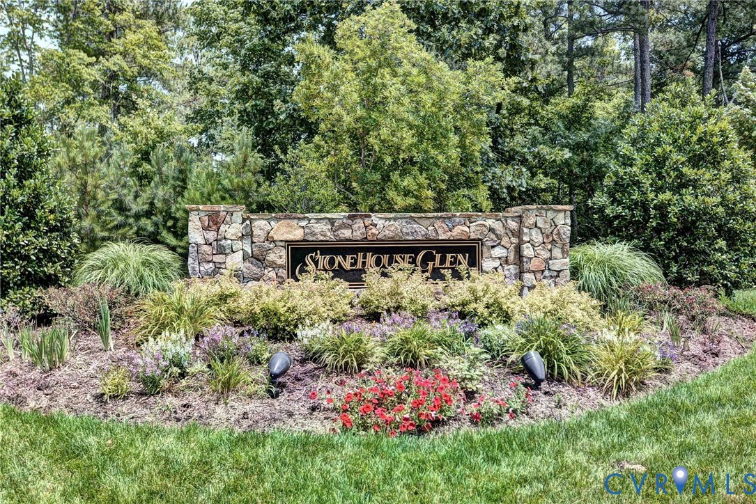 Stone masonry monument sign featuring integrated lighting and mature perennial landscaping