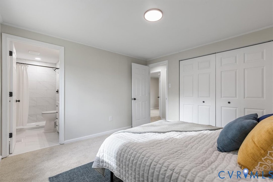 Neutral wall palette, carpeting, dual-panel closet doors, flush-mount lighting, and an entryway to a tiled bathroom with a shower enclosure