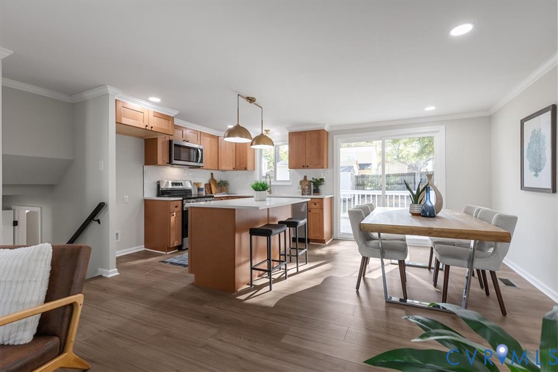 Kitchen featuring light wood-finish cabinetry, a central island with a solid-surface countertop, recessed lighting, and sliding glass doors