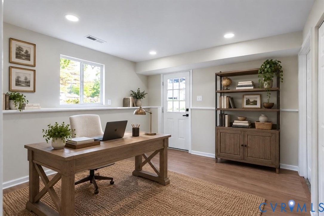 Neutral-toned room with wood-finish flooring, recessed lighting, chair rail detailing, and a multi-pane exterior door