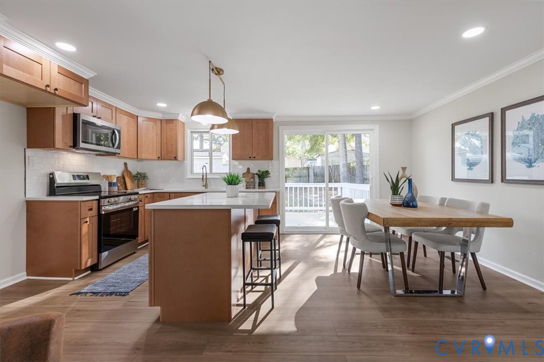 Kitchen featuring shaker-style cabinetry, quartz countertops, a central island with dual pendant lighting, and stainless steel appliances