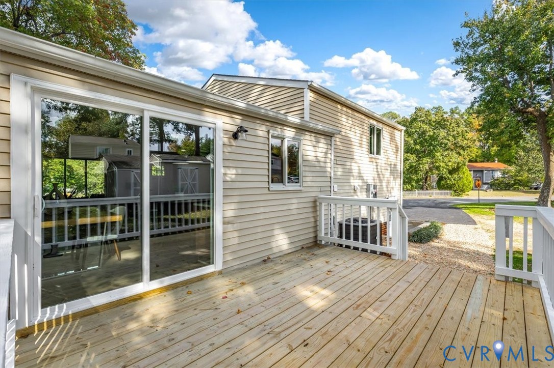 Wood-plank exterior deck featuring white railing and sliding glass door