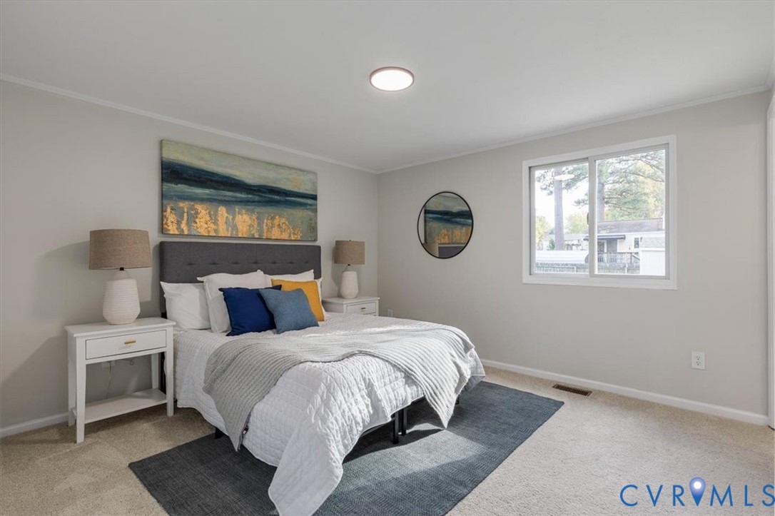 Neutral wall finishes, plush carpeting, and a wide-frame window providing natural illumination