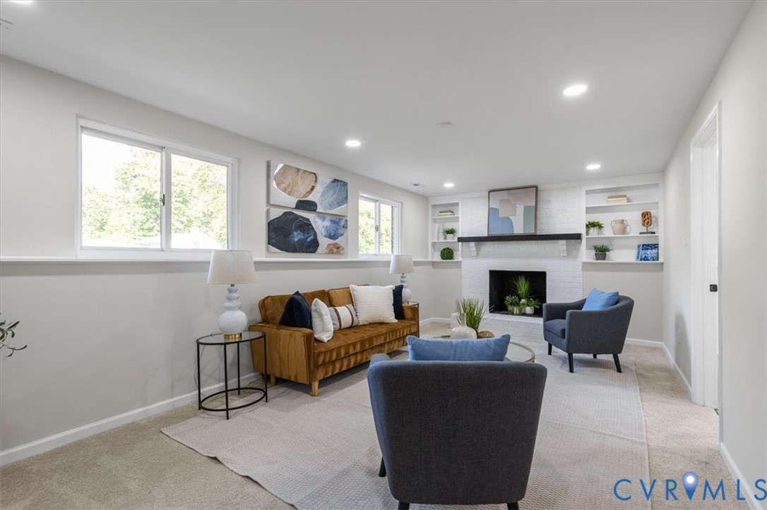 Living area featuring a fireplace with a painted brick surround, a dark wood mantel, recessed lighting, and built-in shelving