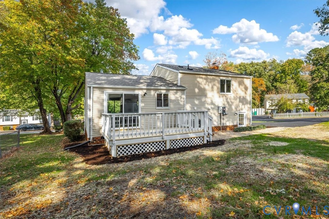 Rear exterior featuring beige siding, an elevated wood deck with white lattice skirting, and glass sliding doors