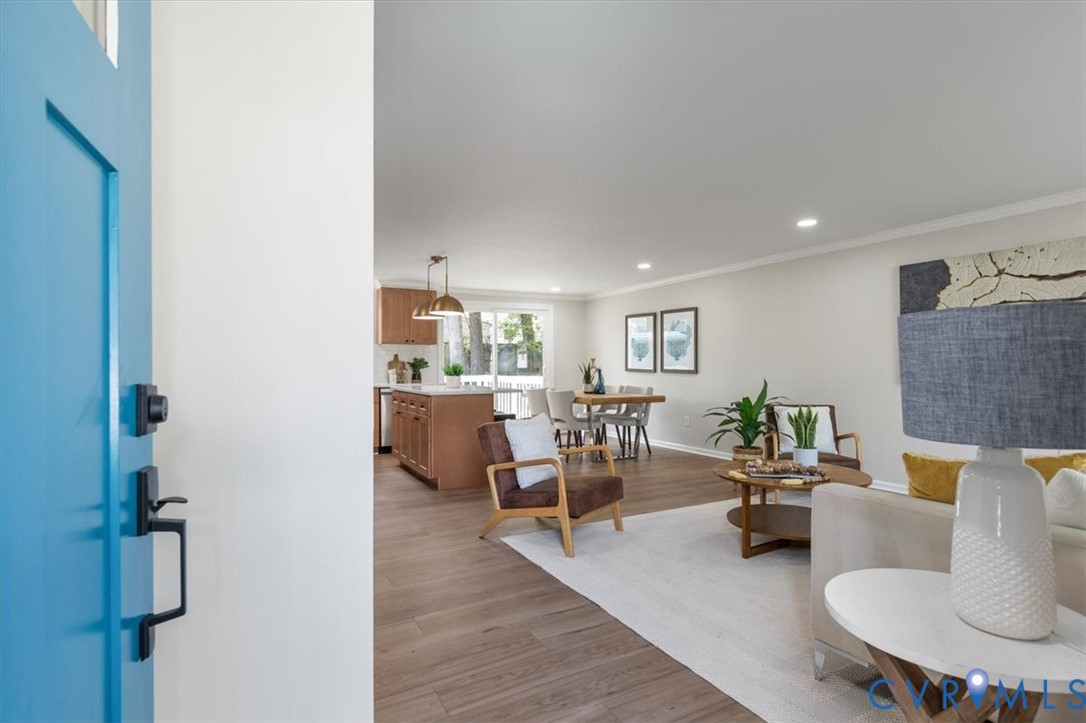 Open-concept interior featuring wood-finish flooring, recessed lighting, and a kitchen island with stone countertop Open-concept interior featuring wood-finish flooring, recessed lighting, and a kitchen island with stone countertop