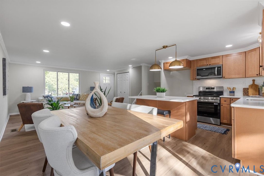 Kitchen featuring shaker-style cabinetry, stainless steel appliances, a central island with countertop seating, recessed lighting, and wood-finish flooring