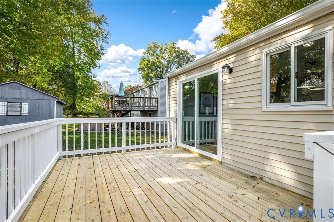 Elevated wood deck featuring white railing and sliding glass door entry