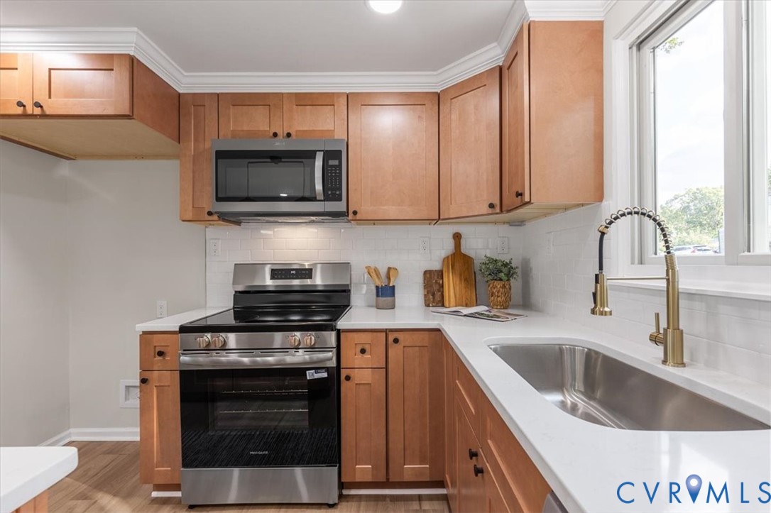 Kitchen featuring shaker-style wood cabinetry, white quartz countertops, white subway tile backsplash, stainless steel appliances, and a gooseneck faucet