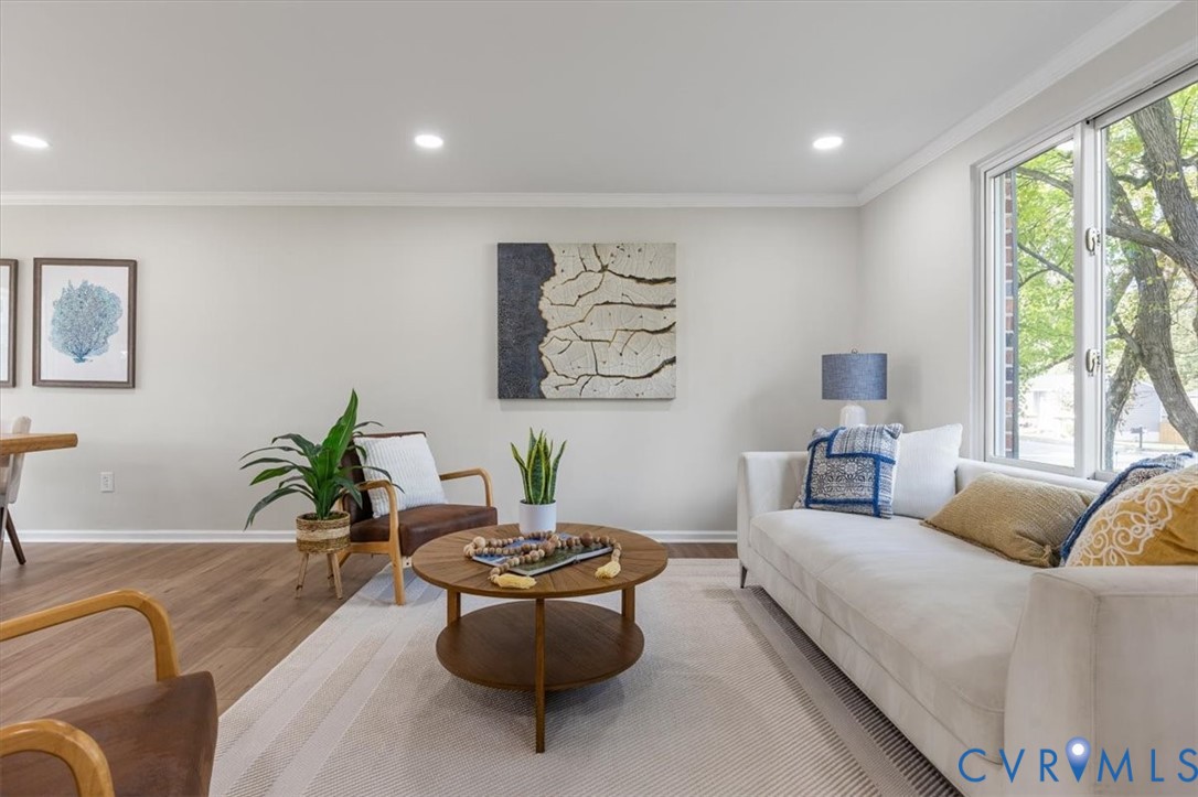 Living area featuring recessed lighting, wood-finish flooring, and large windows with exterior foliage Living area featuring recessed lighting, wood-finish flooring, and large windows with exterior foliage