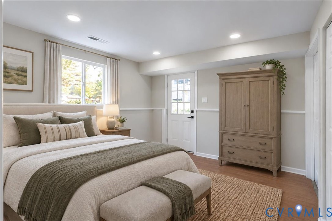 Neutral-toned interior featuring wood-finish flooring, recessed lighting, chair rail molding, and a full-light exterior door