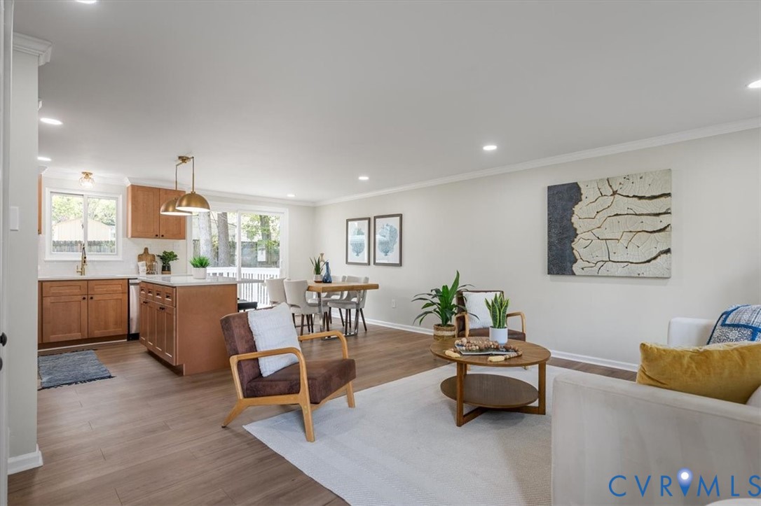 Open-concept living space featuring wood-finish flooring, recessed lighting, kitchen island with stone-finish countertop, and sliding glass doors Open-concept living space featuring wood-finish flooring, recessed lighting, kitchen island with stone-finish countertop, and sliding glass doors