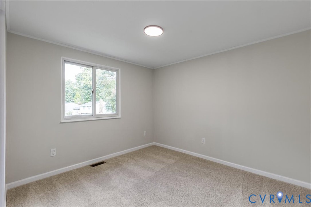 Neutral wall palette featuring wall-to-wall carpeting and a sliding window with clean white trim, accented by a flush-mount circular ceiling light