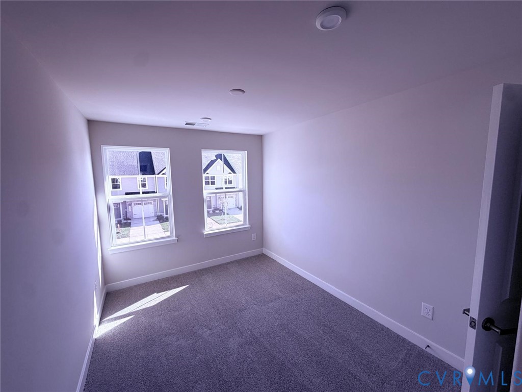 Neutral-toned interior space featuring wall-to-wall carpeting, two double-hung windows, and recessed ceiling lighting
