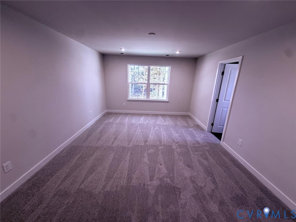 Neutral-toned interior featuring wall-to-wall carpeting, recessed ceiling lighting, and a multi-pane window