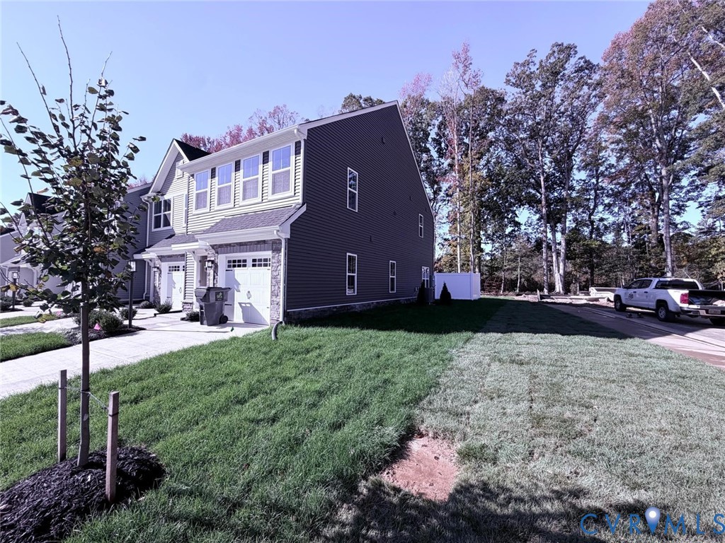Exterior elevation featuring multi-tone horizontal siding, stone veneer accents, an attached two-car garage, and a sodded lawn