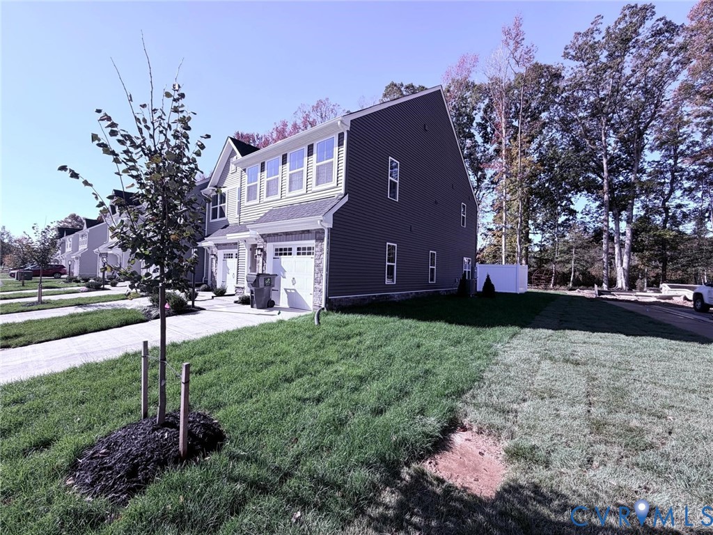Multi-story residence featuring horizontal siding, stone veneer accents, a paved driveway, and an attached garage