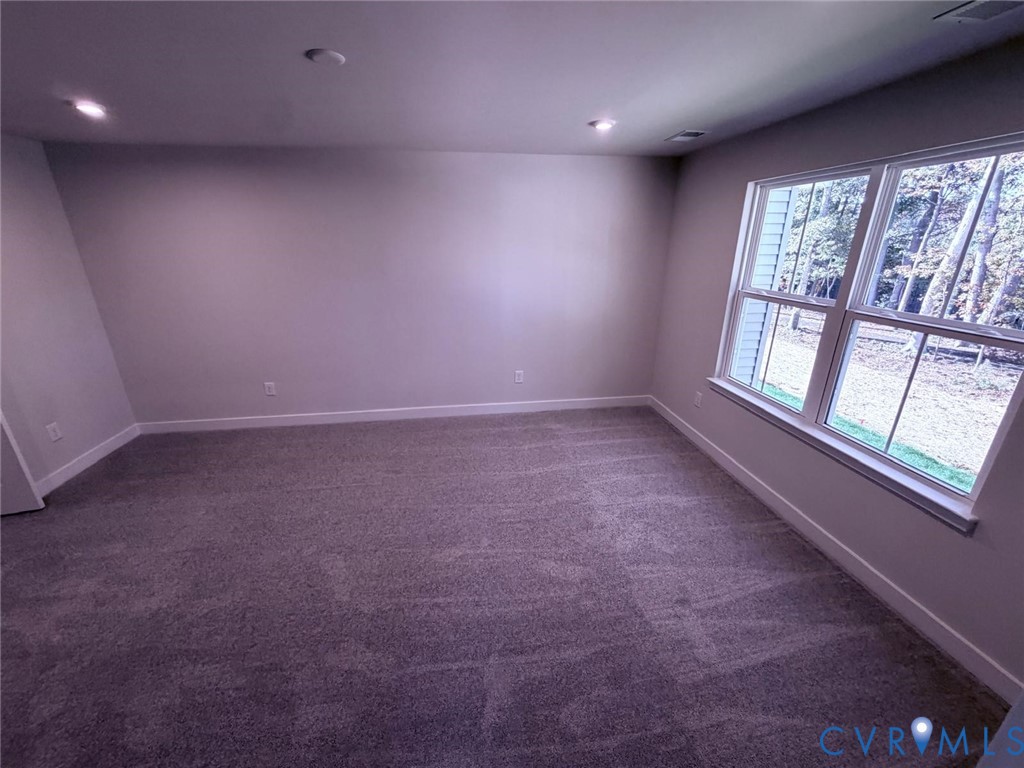 Neutral-toned interior space featuring recessed ceiling lighting, wall-to-wall carpeting, and a large double-hung window
