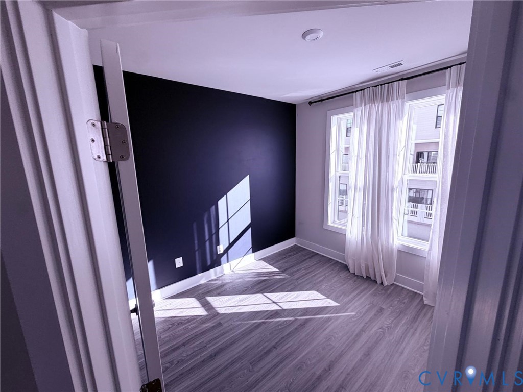 Interior space featuring wood-finish flooring, a dark accent wall, and double-pane windows