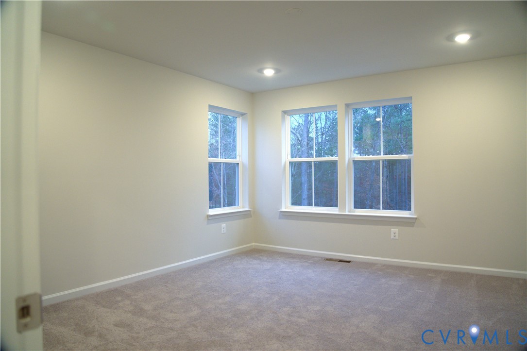 Neutral-toned interior space featuring wall-to-wall carpeting, recessed ceiling lighting, and three double-hung windows Neutral-toned interior space featuring wall-to-wall carpeting, recessed ceiling lighting, and three double-hung windows