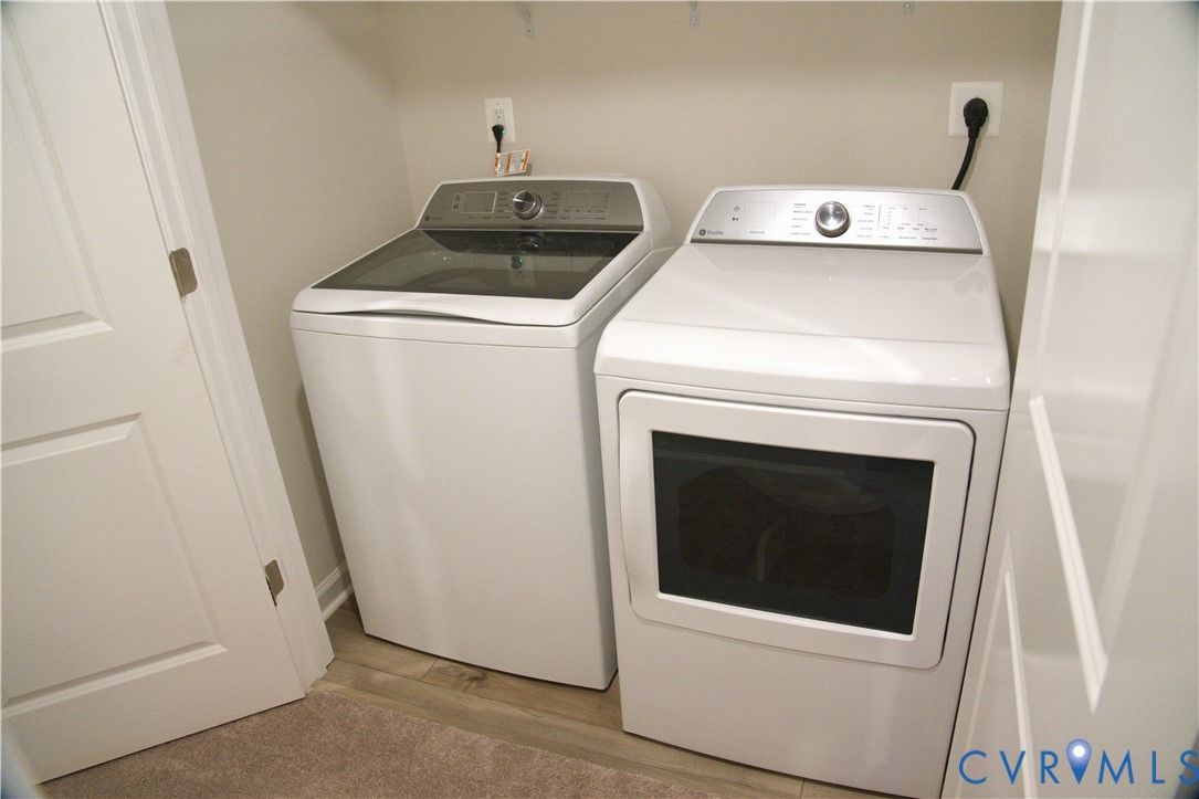 Laundry area featuring white top-load washer and front-load dryer, neutral-toned wall paint, and white interior door