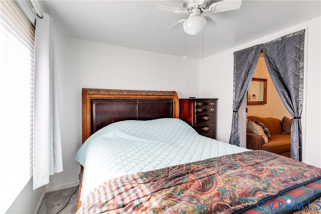 Bedroom featuring a white ceiling-mounted fan with integrated light, pleated window coverings, and neutral wall tones