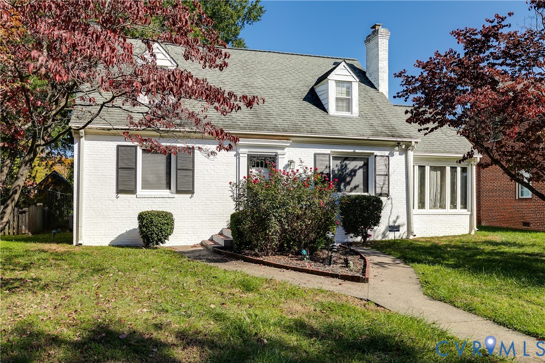 White-painted brick exterior featuring a steep-pitched roof, brick chimney, dormer windows, and decorative shutters White-painted brick exterior featuring a steep-pitched roof, brick chimney, dormer windows, and decorative shutters