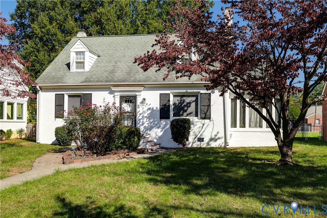 Cape Cod exterior featuring painted brick masonry, a dormer window, louvered shutters, and an attached side sunroom Cape Cod exterior featuring painted brick masonry, a dormer window, louvered shutters, and an attached side sunroom