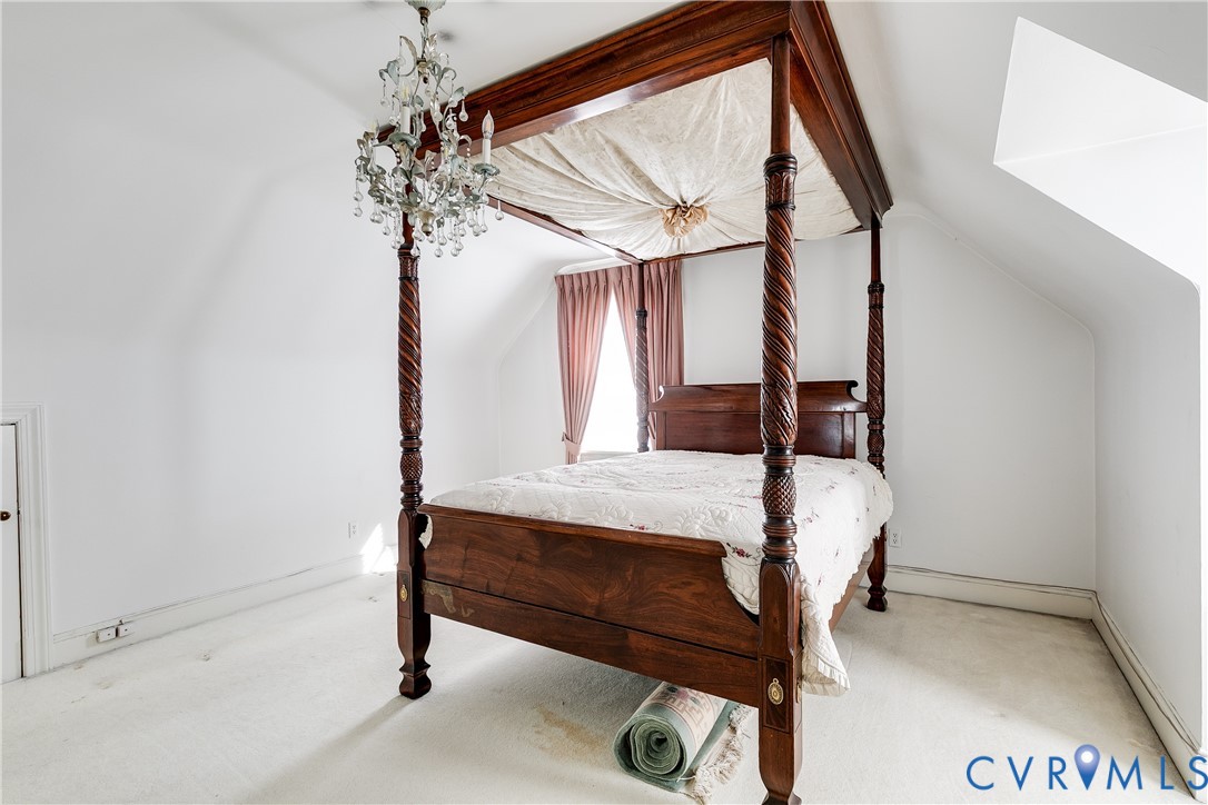 Vaulted ceiling room featuring a multi-tiered crystal chandelier and wall-to-wall carpeting