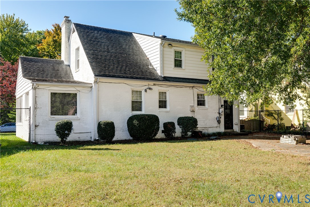 Painted brick exterior, multi-level roofline, vertical siding, chimney, and stone-paved patio area
