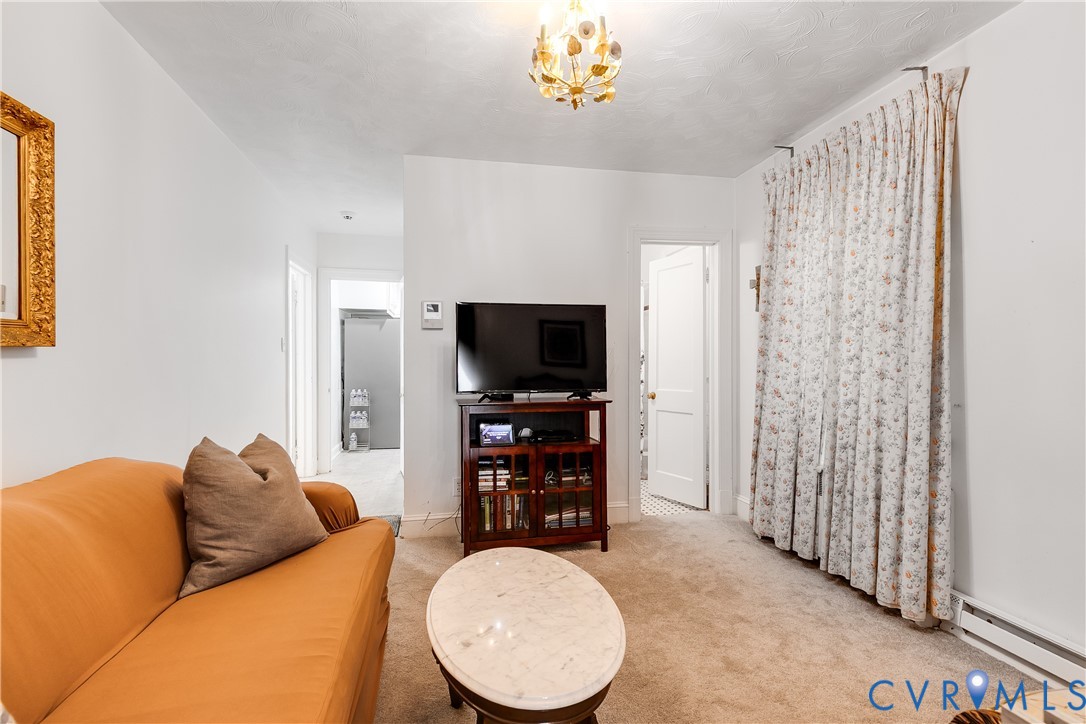 Interior room featuring neutral wall-to-wall carpeting and an ornate, multi-bulb gold-tone chandelier