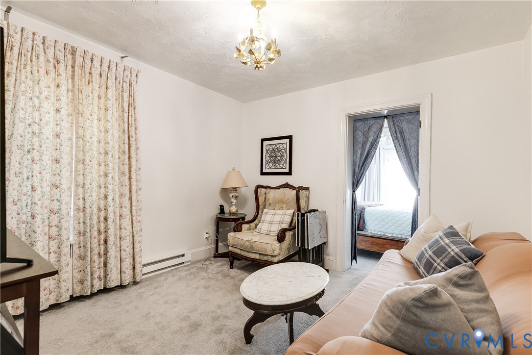 Neutral wall-to-wall carpeting, decorative multi-arm chandelier, and classic door frame architecture