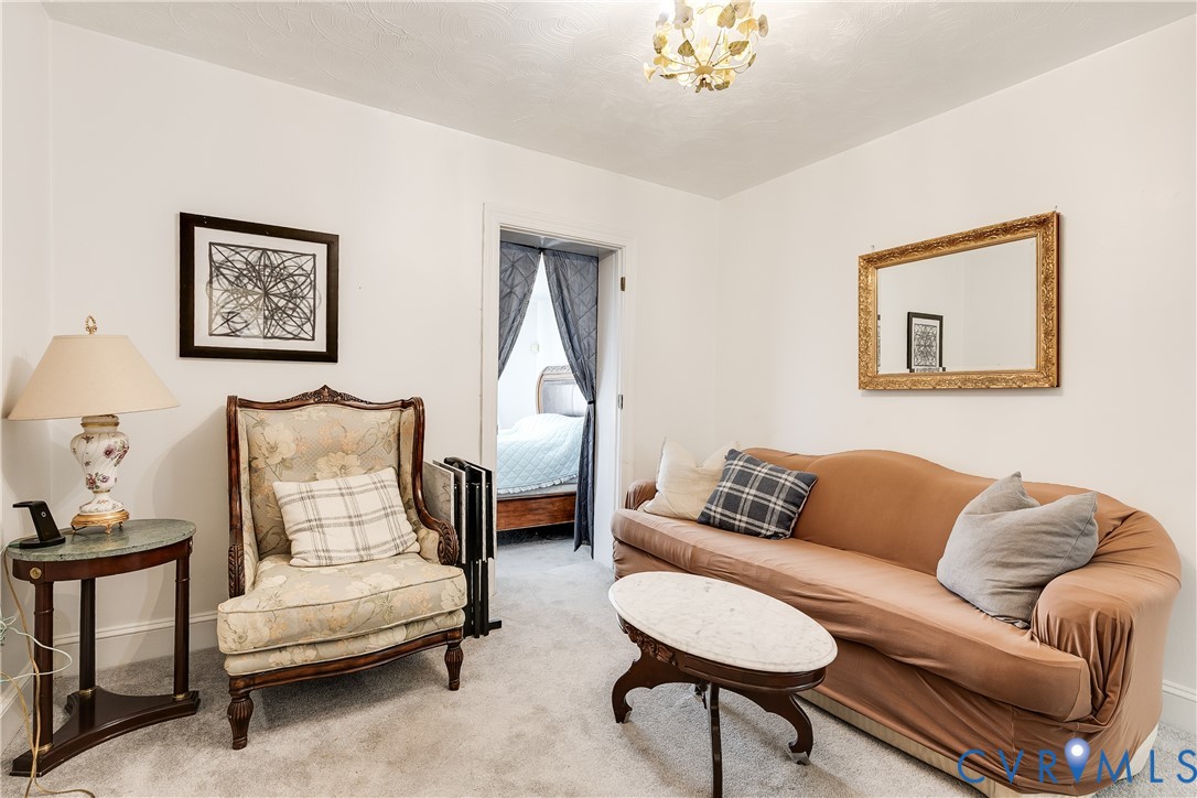 Interior space featuring neutral wall tones, carpeted flooring, and a decorative multi-bulb ceiling fixture