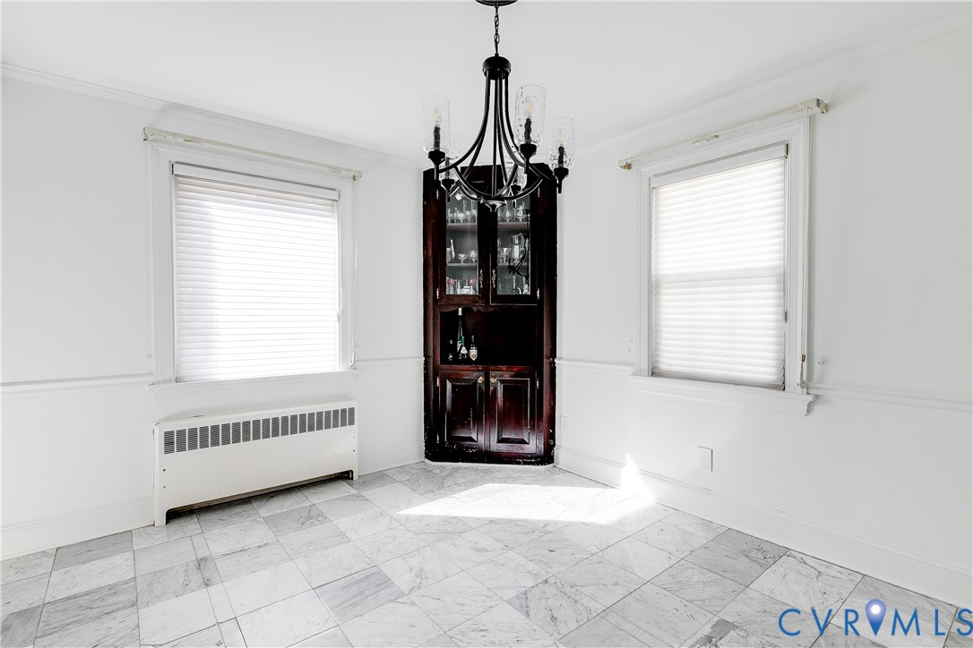 Built-in corner cabinetry, stone-finish tile flooring, decorative chandelier, and wall wainscoting
