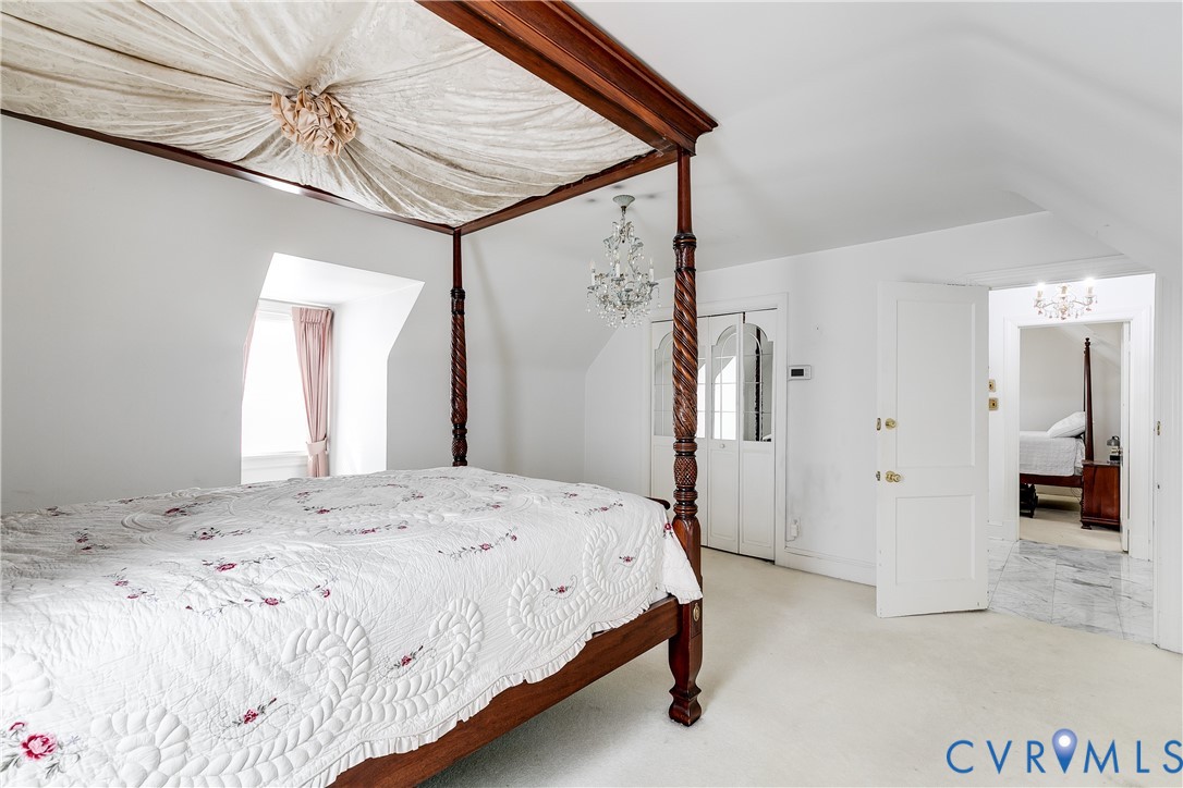 Vaulted ceilings featuring a dormer window, closet with mirrored doors, and a crystal chandelier