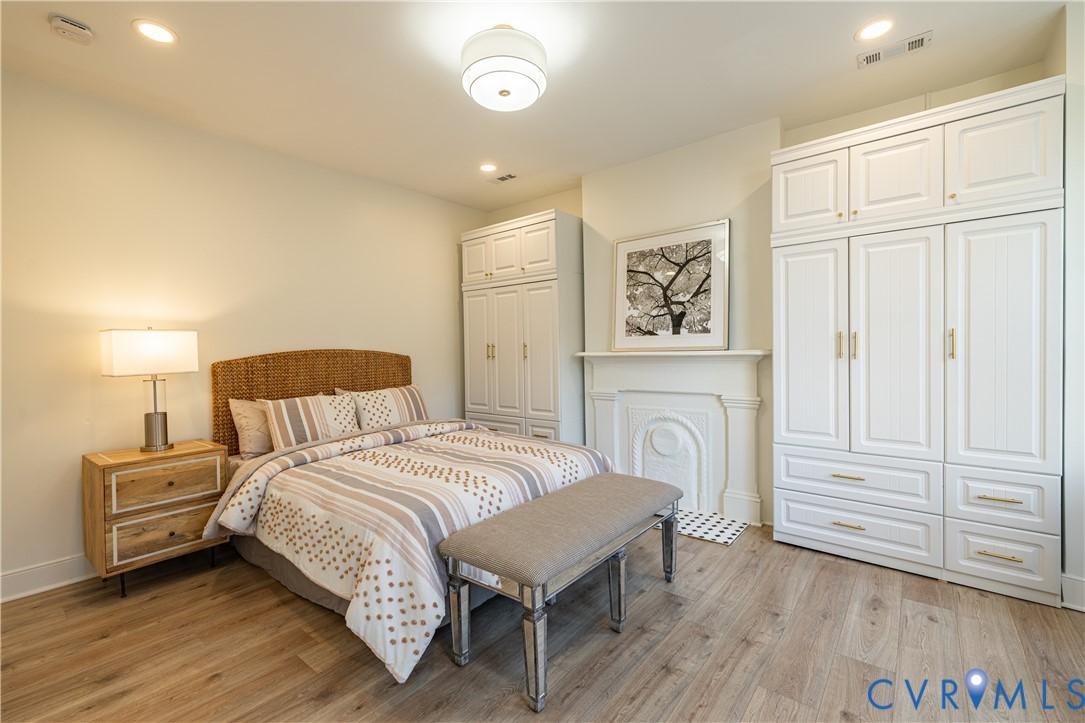 Room featuring wood-finish flooring, built-in white cabinetry, and a decorative fireplace surround