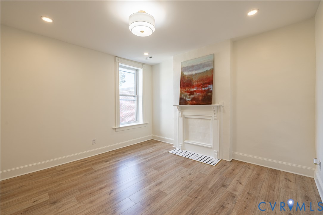Interior space featuring wood-finish flooring, a decorative fireplace mantel, recessed lighting, and a modern semi-flush mount ceiling fixture