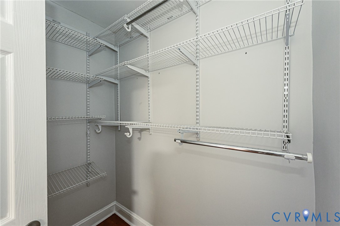 Walk-in closet featuring white wire shelving, wall-mounted adjustable tracks, and integrated garment rods