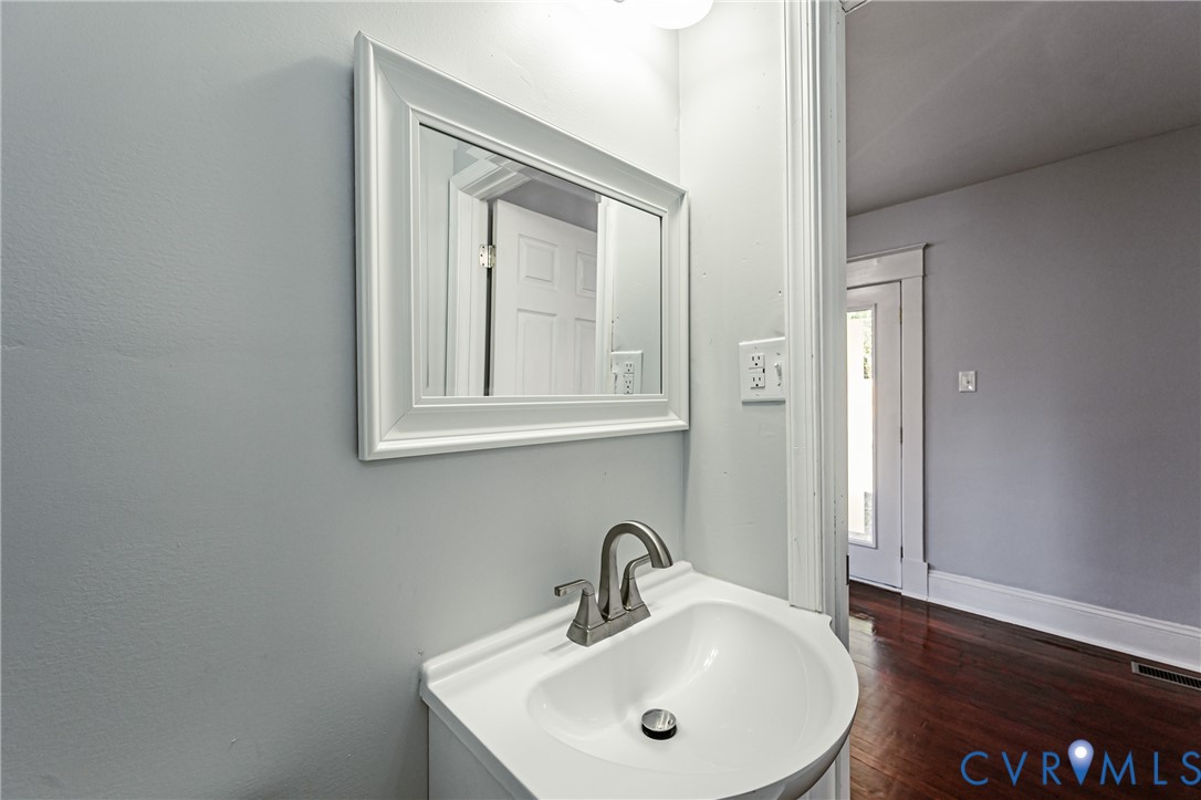 Wall-mounted vanity featuring a white basin, metallic faucet, and framed mirror with integrated lighting