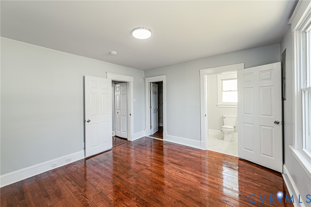Room featuring wood-finish flooring, white six-panel interior doors, and neutral wall tones