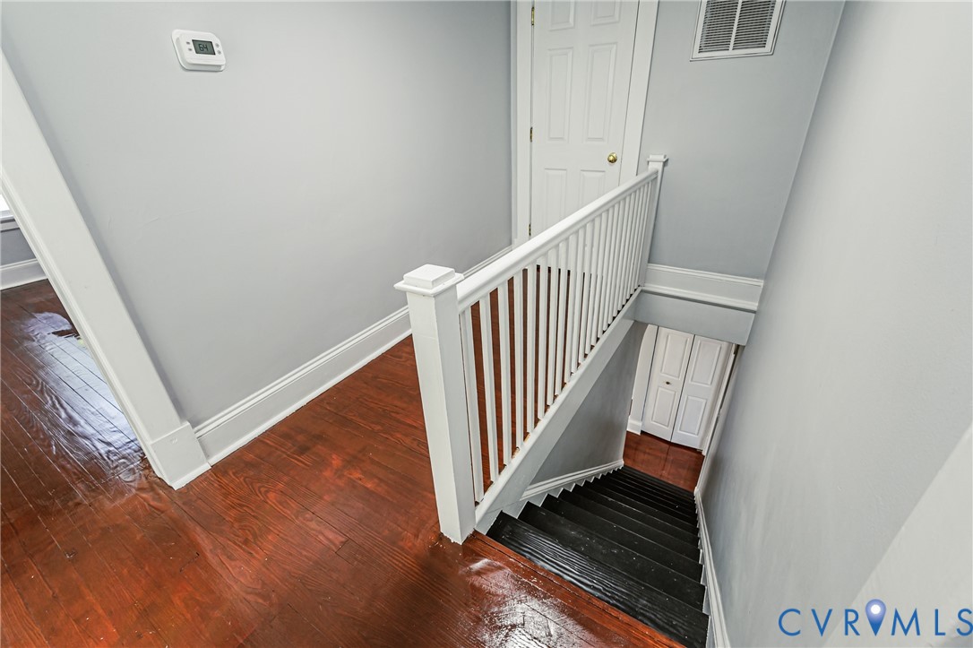 Wood-finish flooring, white spindle staircase railing, and painted interior doors