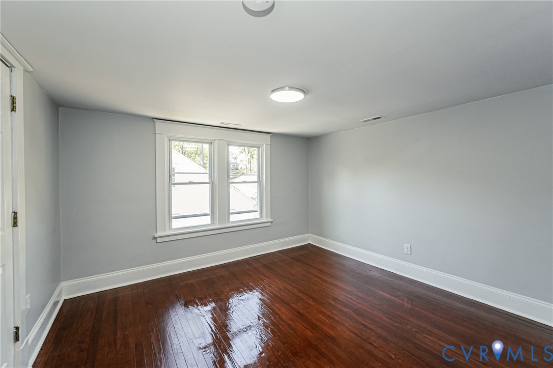 Refinished wood-finish flooring, neutral wall tones, double-pane window with traditional molding, and overhead flush-mount lighting