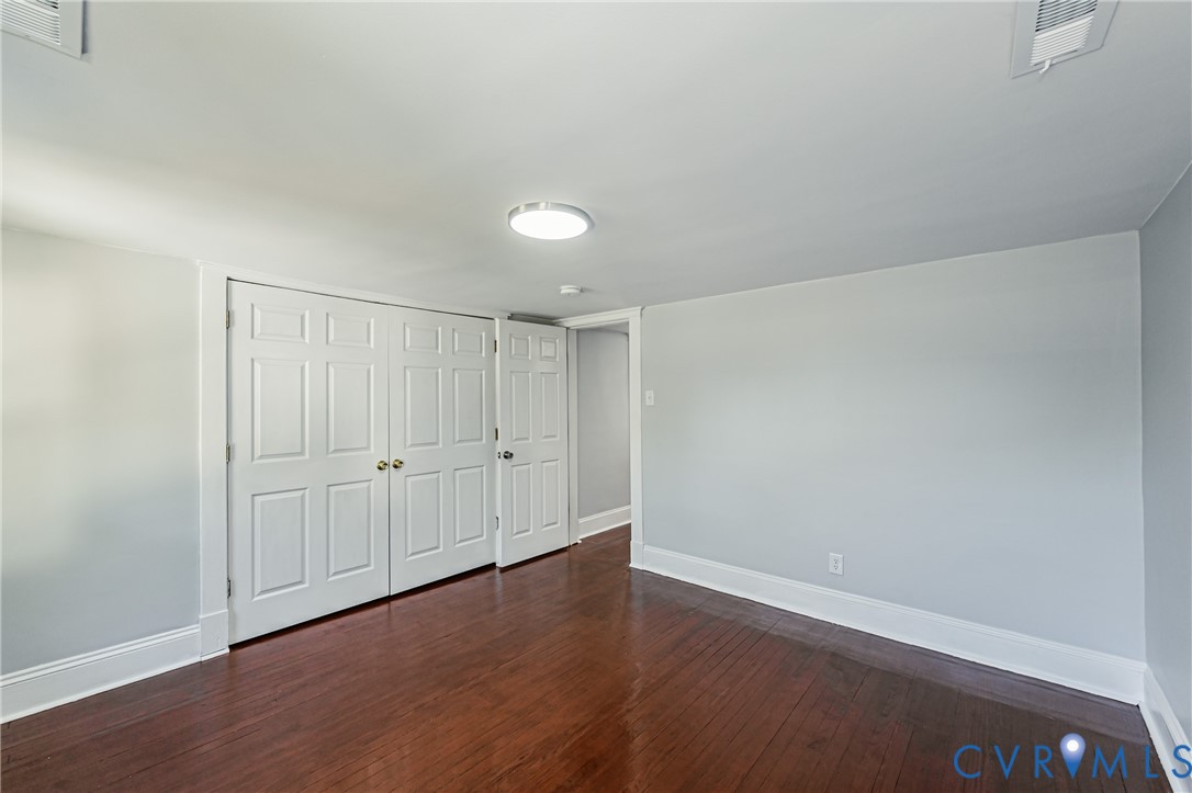 Interior room featuring wood-finish flooring, white panel doors, and a central flush-mount ceiling light